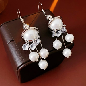 Detailed view of pearl tassel earrings featuring zircon studs on a premium leather stand