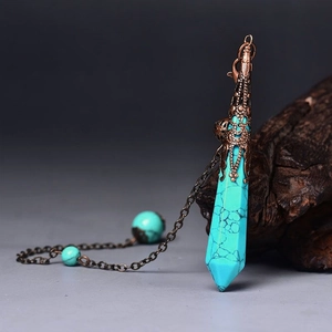 Detail of turquoise hexagonal pendant with antique bronze filigree cap on wood