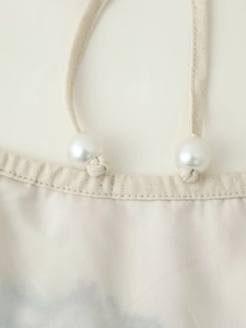 Détail de la texture en coton avec perles blanches et bride en corde nouée du haut