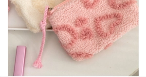Detail of pink plush toiletry bag with textured dots and woven zipper pull cord