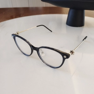 Detail of round frame glasses with black tortoiseshell front and golden metal temples