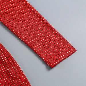 Macro shot of red knit fabric with sparkling gold rhinestones and stud details