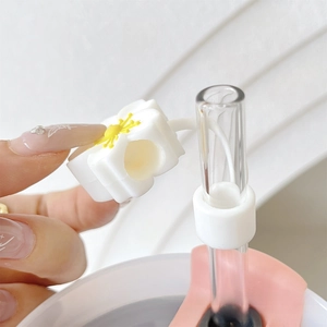 Close-up of white daisy silicone straw cover with yellow center on 10mm glass straw