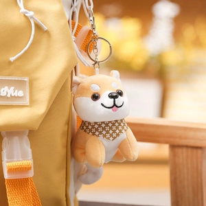 Cute Shiba Inu plush keychain with floral scarf attached to a yellow backpack detail