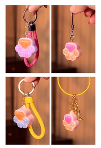 Collage of four glittery cat paw resin keychains in pink, purple, and blue colors