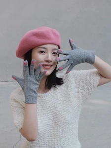 Detailed view of grey knitted gloves with pink nail-tip accents and pink wool beret