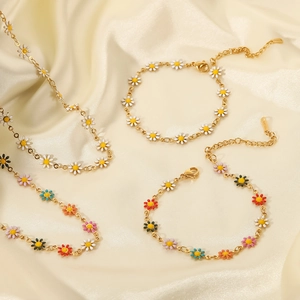 Conjunto de joyas de titanio bañadas en oro 18K con margaritas sobre seda beige