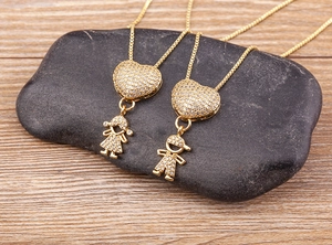 Dettaglio di ciondoli a cuore placcati oro 18k con figure di bimbi e zirconi incastonati