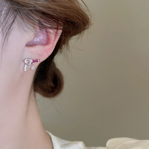 Detailed close-up of a silver heart earring with pink and purple zircon stones on a model