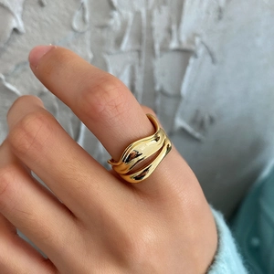 Minimalist double-layered irregular wave ring in gold finish on a model's hand
