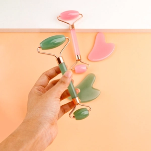 Detail of pink and green resin facial roller and heart shaped gua sha massage tools