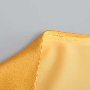 Détail macro du tissu satiné doré de haute qualité avec des coutures précises et reflets perlés