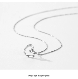 Macro shot of silver heart pendant with fine small diamond accents on a delicate chain