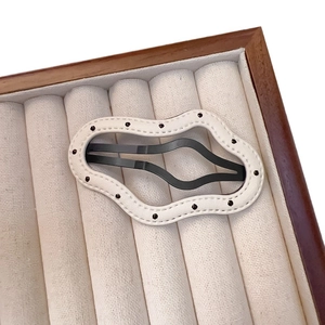 Chic wave-shaped PU leather hair clip with black polka dots on ivory velvet tray