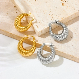 Twisted hoop earrings in gold and silver finish on elegant beige stone blocks