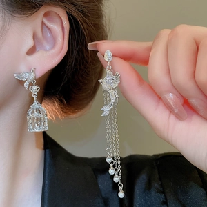 Details von asymmetrischen Vogelohrringen in Silber mit Käfig und langen Perlenquasten