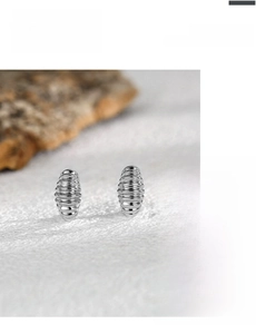 Macro detail of silver croissant hoop earrings with a textured threaded metal finish
