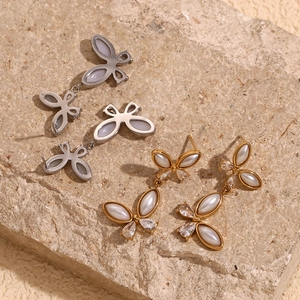Detail of 18K gold plated butterfly earrings with pearls and crystals on beige stone