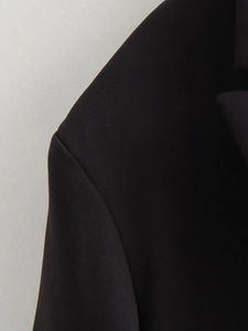 Macro detail of black blazer shoulder and lapel showing fine textured fabric quality