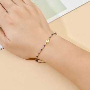 Close-up of bohemian golden lightning pendant bracelet with delicate blue beads on wrist