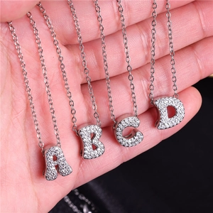 Silver micro-paved zircon A-D alphabet necklaces held against a dark background