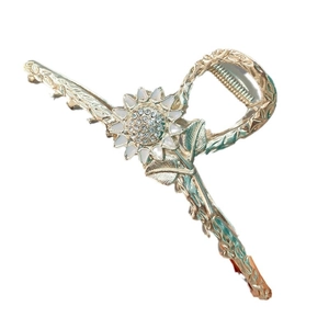 Pinza per capelli a girasole dorata con strass bianchi e petali su fondo bianco