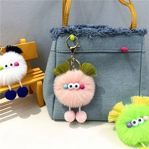 Cute plush monster bag charm with pom-pom legs on blue denim bag and mini wooden stool