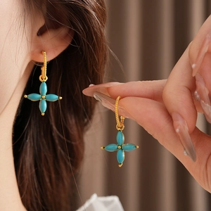 Detailed view of vintage gold-plated four-leaf clover earrings with turquoise stone inlay