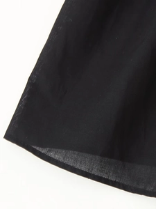 Detail of the black cotton-linen shirt hem showing fabric texture and fine stitching