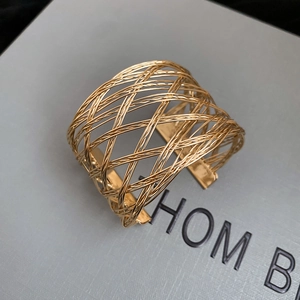 Close-up of golden wide mesh hollow cuff bracelet with polished woven texture