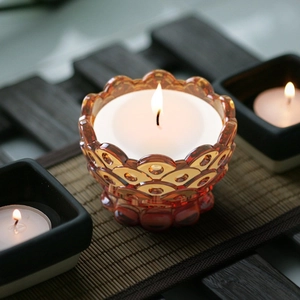 Amber glass candle holder with petal-shaped edges on a zen-style bamboo background