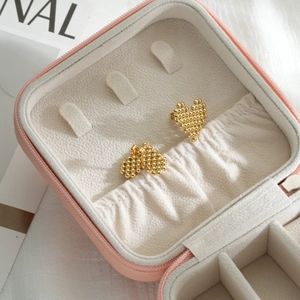 Minimalist gold heart-shaped bead earrings displayed in a pink jewelry box on soft fabric