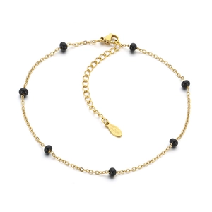 Golden stainless steel flat cross chain anklet with black enamel beads on white background