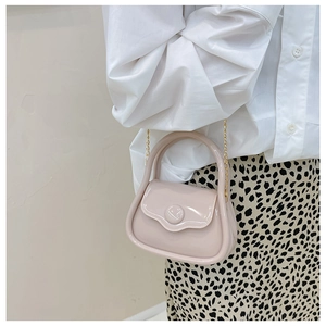Close-up of mini pink jelly handbag with round buckle and delicate gold chain strap