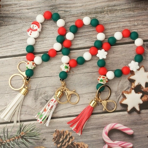 Christmas silicone bead wristlet with wooden beads, tassel and festive charms on wood