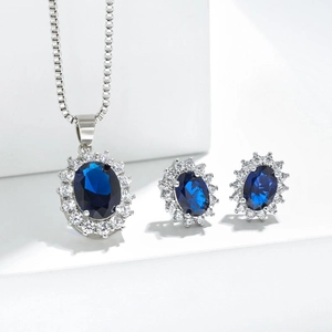 Deep blue sapphire necklace and earrings set with halo crystal accents on white pedestals