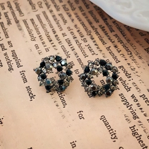 Close-up of vintage dark style circular earrings with sparkling rhinestones on old paper
