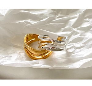 Close-up of minimalist gold and silver wavy stackable rings on white textured background