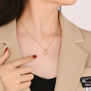 Elegant gold hollow heart pendant necklace worn on neck with stylish beige suit jacket