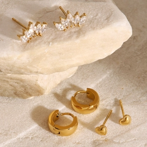 Three pairs of golden stainless steel earrings with zircons and heart shapes on stone