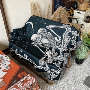 Detail of woven camping blanket featuring gothic skeleton lovers and floral fringe edge