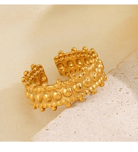 Detailed macro view of the gold beaded texture on the stainless steel open ring