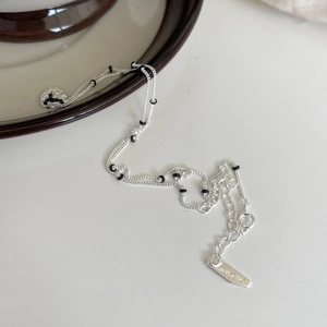 Macro shot of 925 silver beaded necklace with black enamel beads on a white surface
