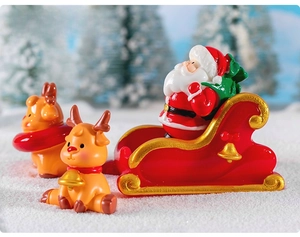 Miniature resin Santa Claus in red sleigh with two cute reindeer on snow scene decoration
