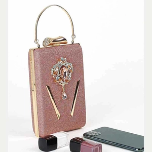 Detail van roségouden avondtas met lovertjes, kristallen ornament en metalen greep