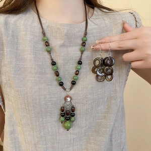 Detail view of retro coconut shell necklace and tassel earrings worn on a model