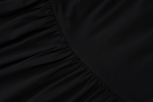 Macro shot of high-density knit fabric showing detailed ruched pleats on black dress