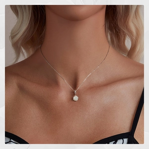 Detailed close-up of a white rose flower pendant on a 925 silver chain worn by a model