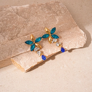 Detailed view of flower earrings with blue crystals and water drop tassels on stone