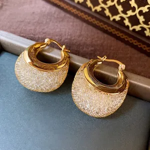 Golden mesh wide hoop earrings with sparkling crystals on dark vintage background